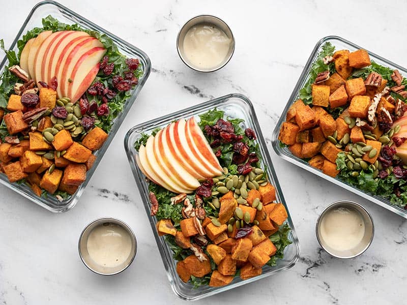 This fresh and crisp Autumn Kale and Sweet Potato Salad is chock full of fresh produce, but still has all those cozy fall flavors! Budgetbytes.com meal prep containers full of autumn kale and sweet potato salad