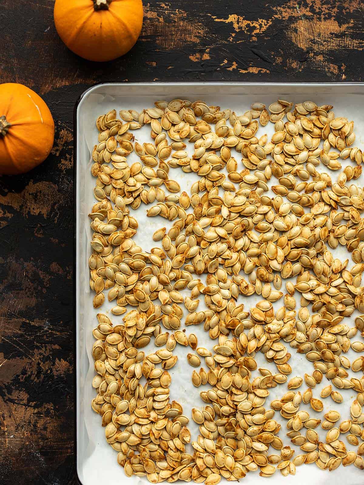 Roasted pumpkin seeds are an easy and deliciously crunchy byproduct of pumpkin carving. A fast, easy, and tasty fall treat! Budgetbytes.com Overhead view of a sheet pan full of roasted pumpkin seeds.