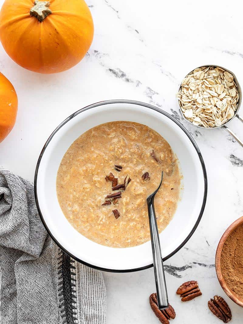 Pumpkin Pie Overnight Oats are a great way to use up leftover pumpkin purée and are a delicious make-ahead breakfast for busy mornings. Budgetbytes.com Overhead view of a bowl of overnight pumpkin pie oats with pumpkins, oats, and pecans on the side