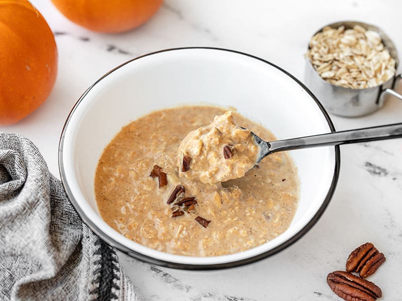Pumpkin Pie Overnight Oats are a great way to use up leftover pumpkin purée and are a delicious make-ahead breakfast for busy mornings. Budgetbytes.com Side view of a spoon lifting some pumpkin pie overnight oats out of the bowl