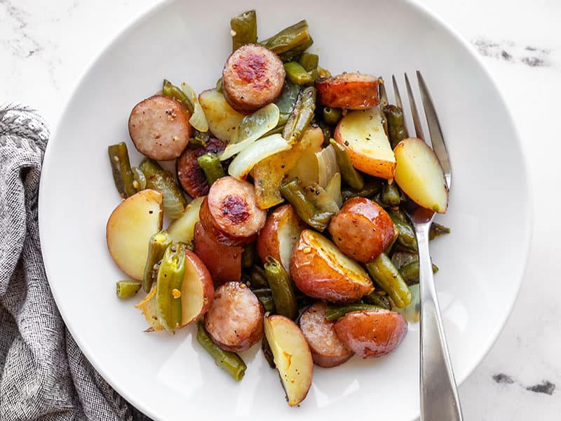Sheet pan meals don't get an easier or more delicious than this Sheet Pan Kielbasa Potatoes and Green Beans dinner. Budgetbytes.com Sheet pan kielbasa, potatoes, and green beans in a bowl with a fork