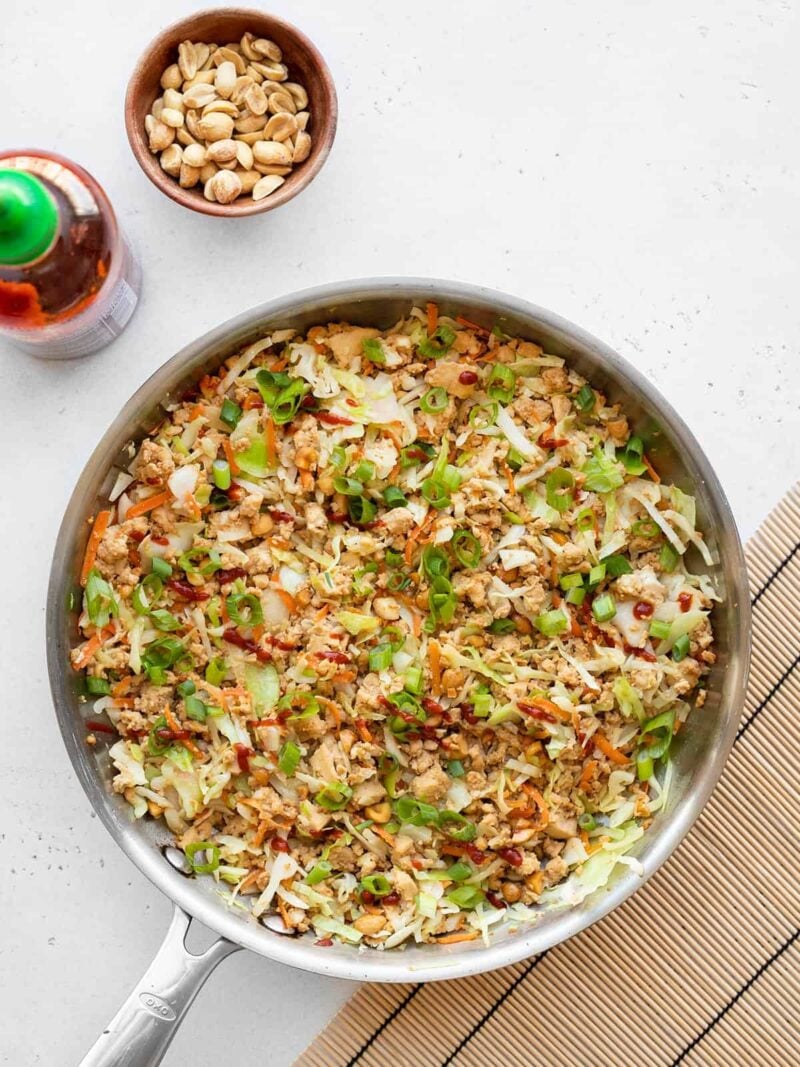 This super fast and inexpensive tofu stir fry is super filling, easy enough for busy weeknights, and endlessly customizable! Budgetbytes.com Quick Tofu Stir Fry in a skillet with sriracha and a bowl of peanuts on the side