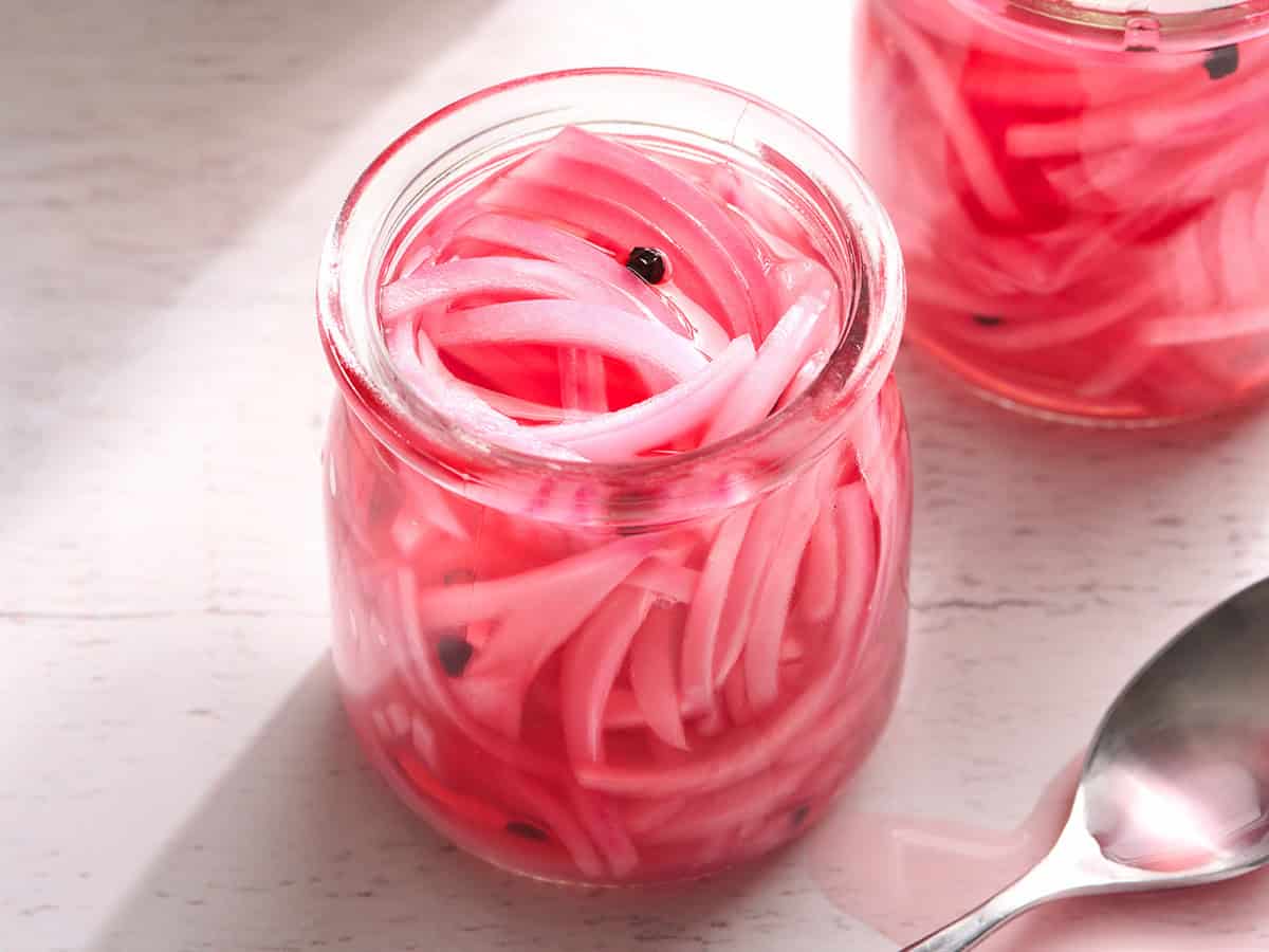 Side view of a jar of homemade picked red onions.