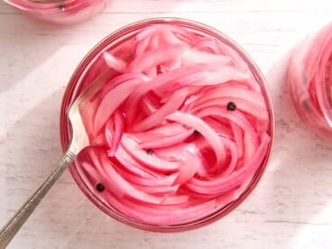 Overhead view of a jar of pickled red onions with a fork.