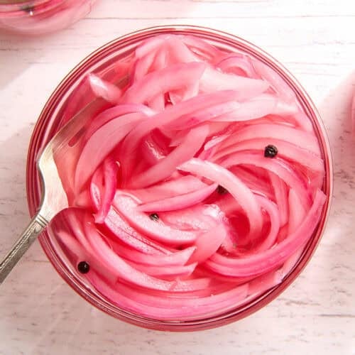 Overhead view of a jar of pickled red onions with a fork.