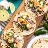 Three Tajín Shrimp Tacos open faced on a wooden board