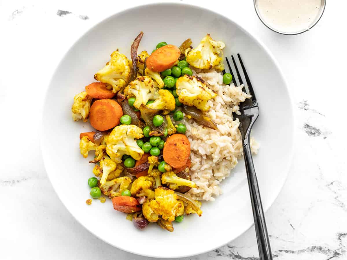 Overview of curry roasted vegetable bowls with lemon tahini dressing on the side