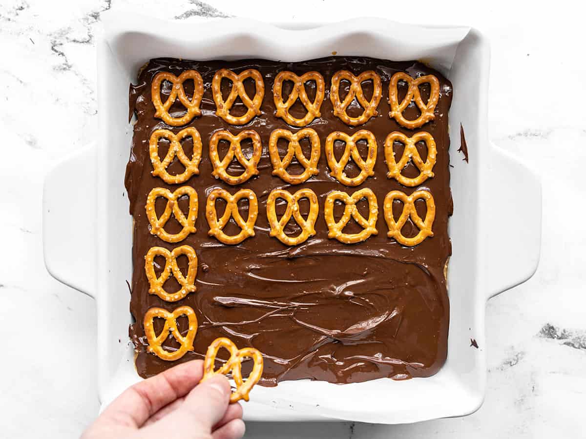 Mini pretzels being pressed into the melted chocolate