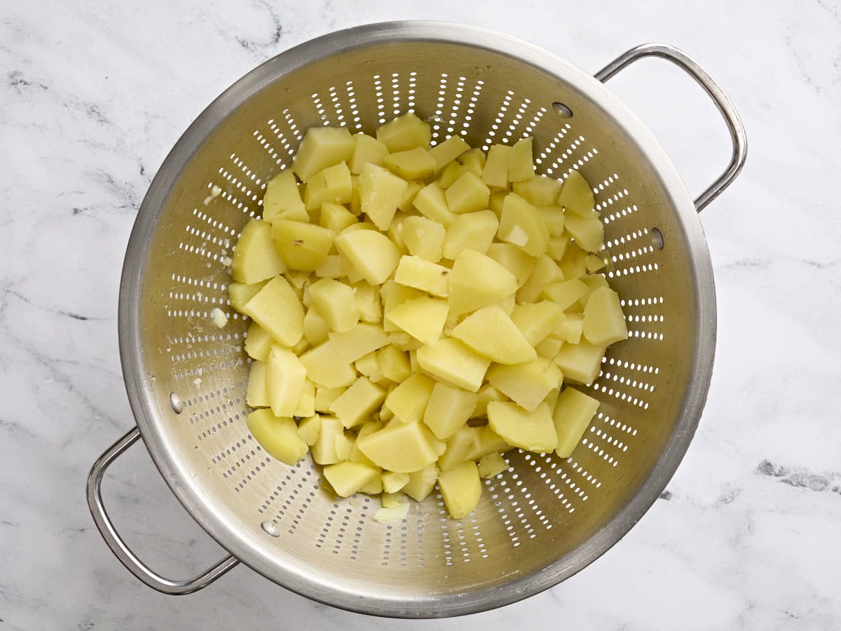 Cooked and cubed potatoes in a colander.