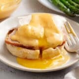 Hollandaise sauce on eggs and ham and an english muffin.
