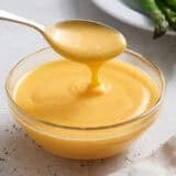 Homemade hollandaise sauce in a bowl with a spoon.