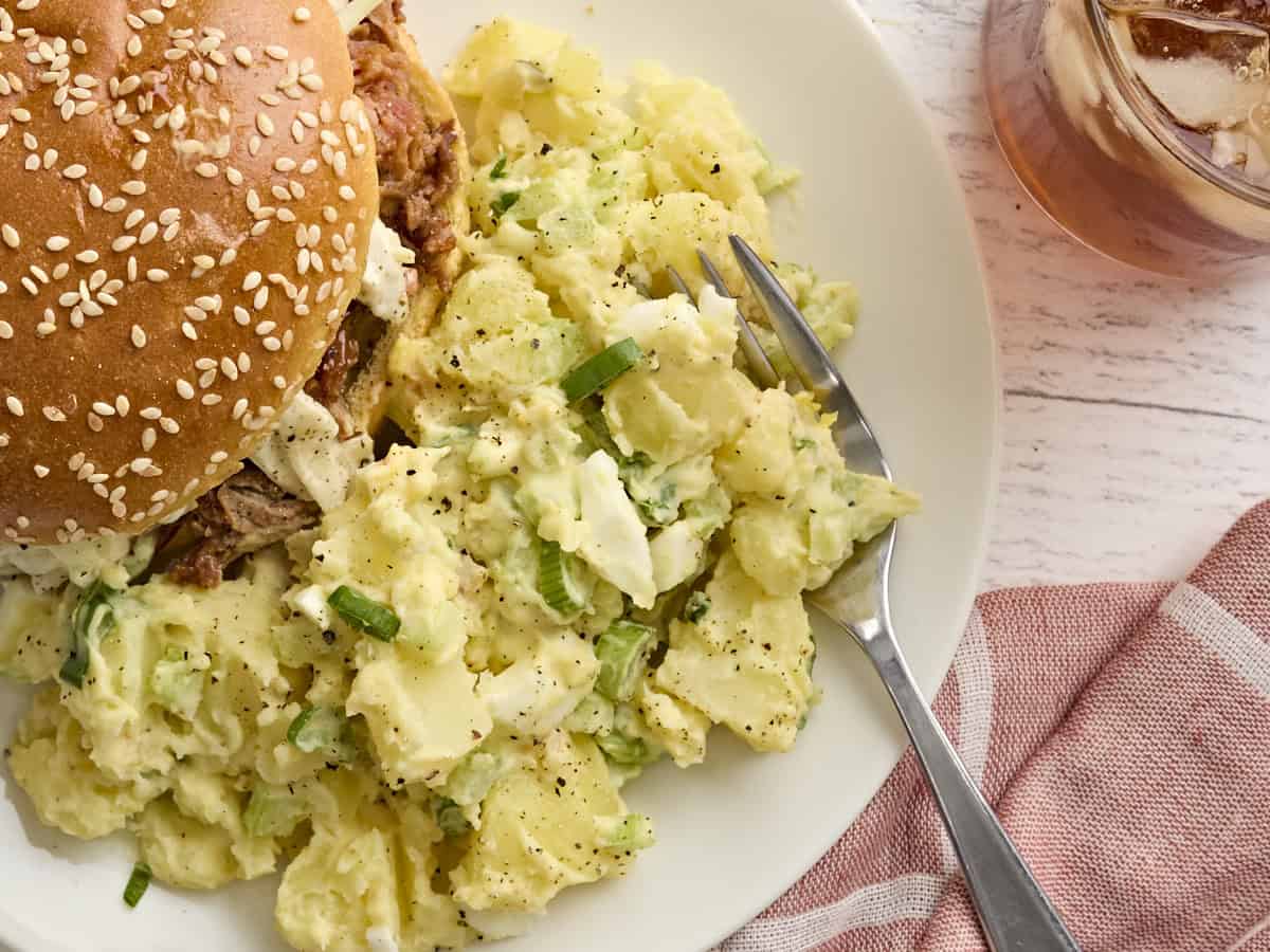Overhead view of Southern potato salad on a plate with a sandwich.