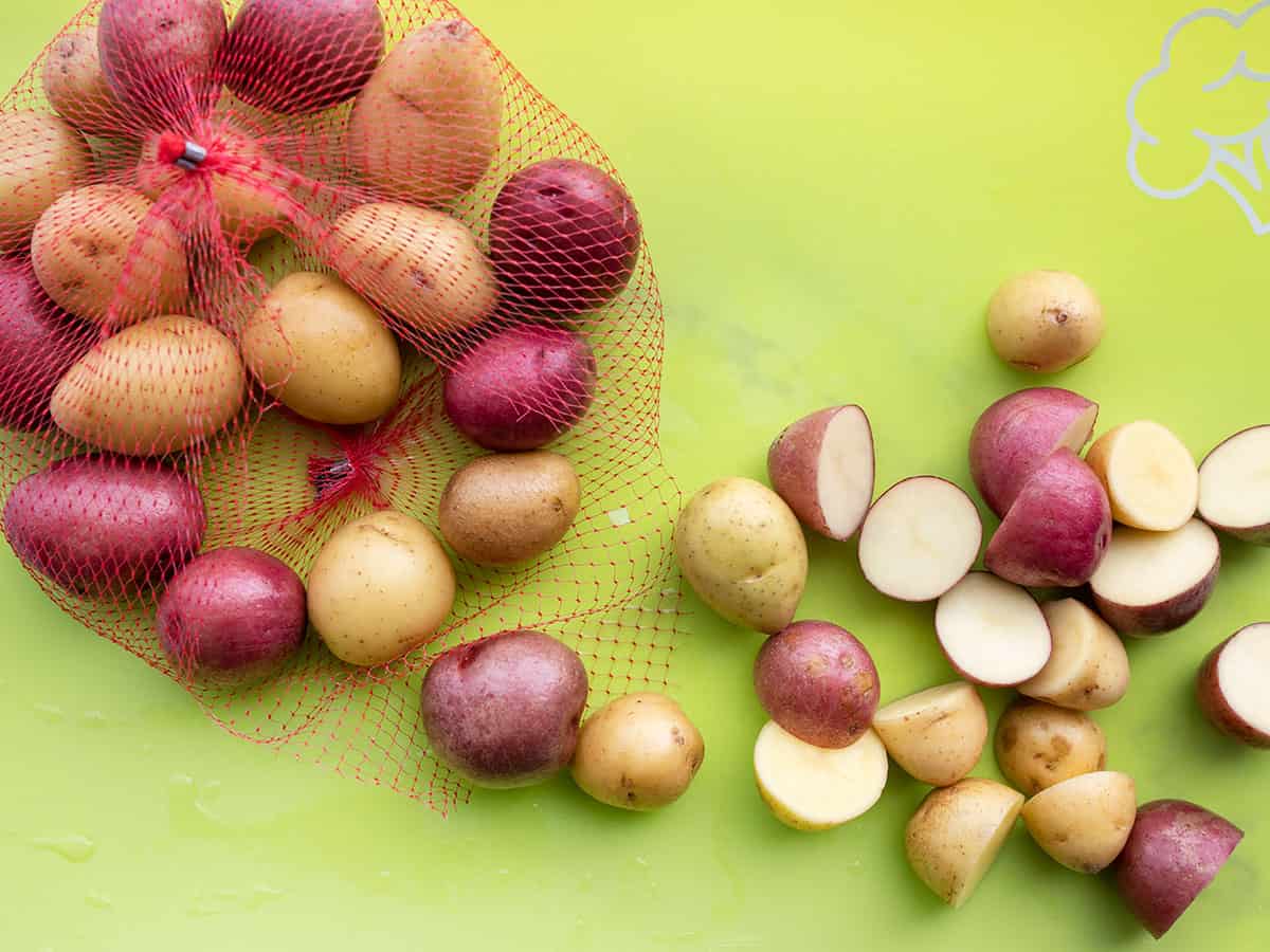 Cut baby potatoes on a cutting board.