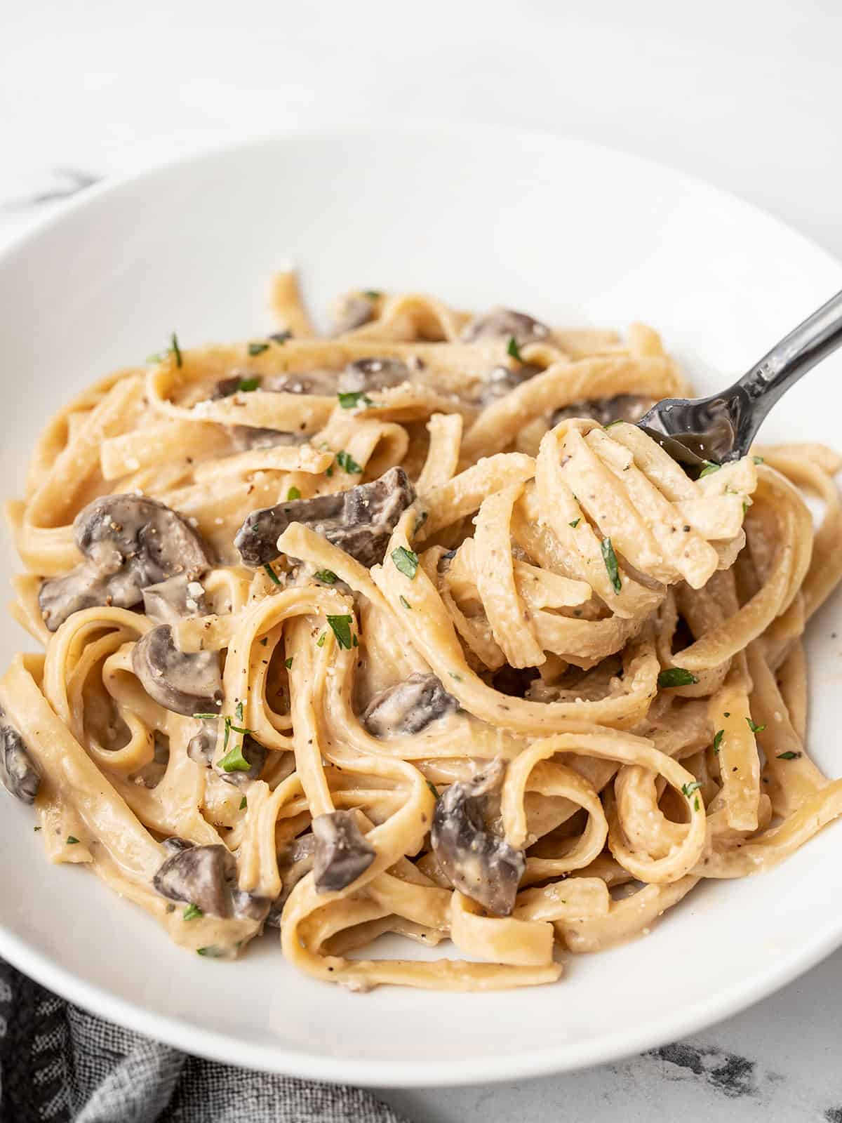 A fork twirling creamy mushroom pasta on a plate