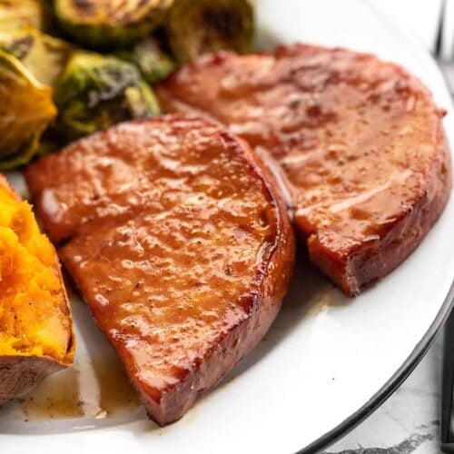 Side view of glazed ham steaks on the plate with sides