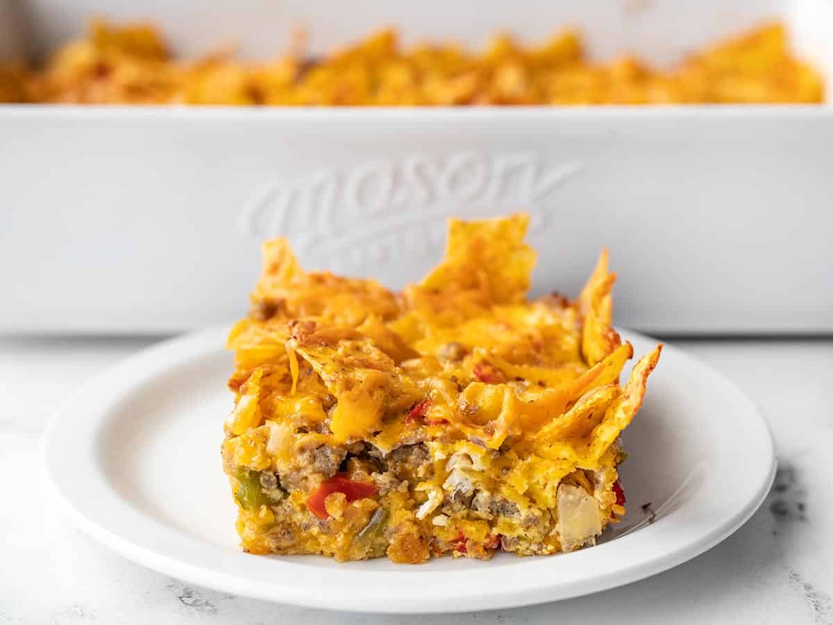 one slice of breakfast casserole on a plate in front of the casserole dish