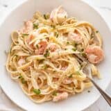 Shrimp alfredo pasta in a bowl with a fork on the side