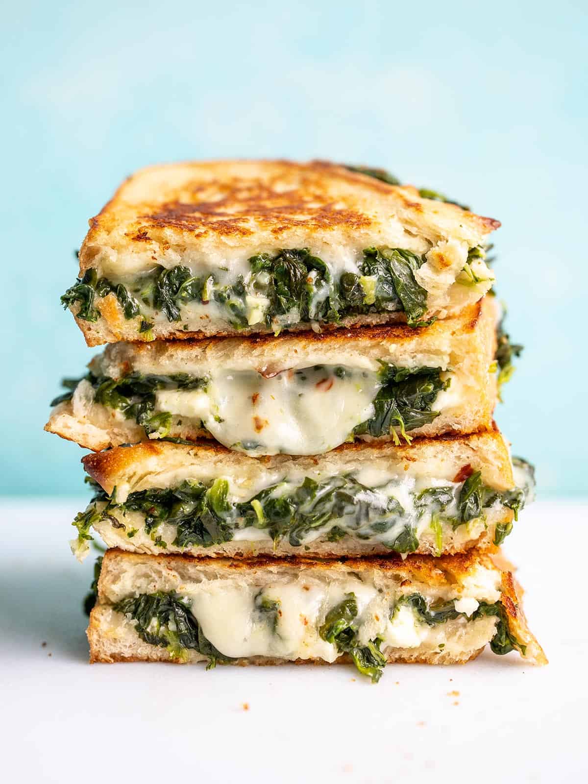 A stack of spinach and feta grilled cheese sandwich halves.