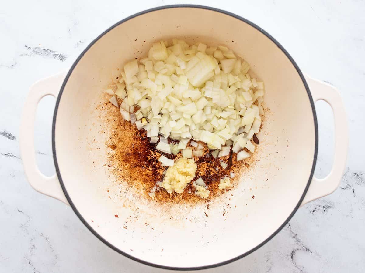 Diced onion and minced garlic added to the pot with bacon grease.