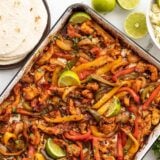 Sheet pan full of chicken fajitas with rice and tortillas on the side