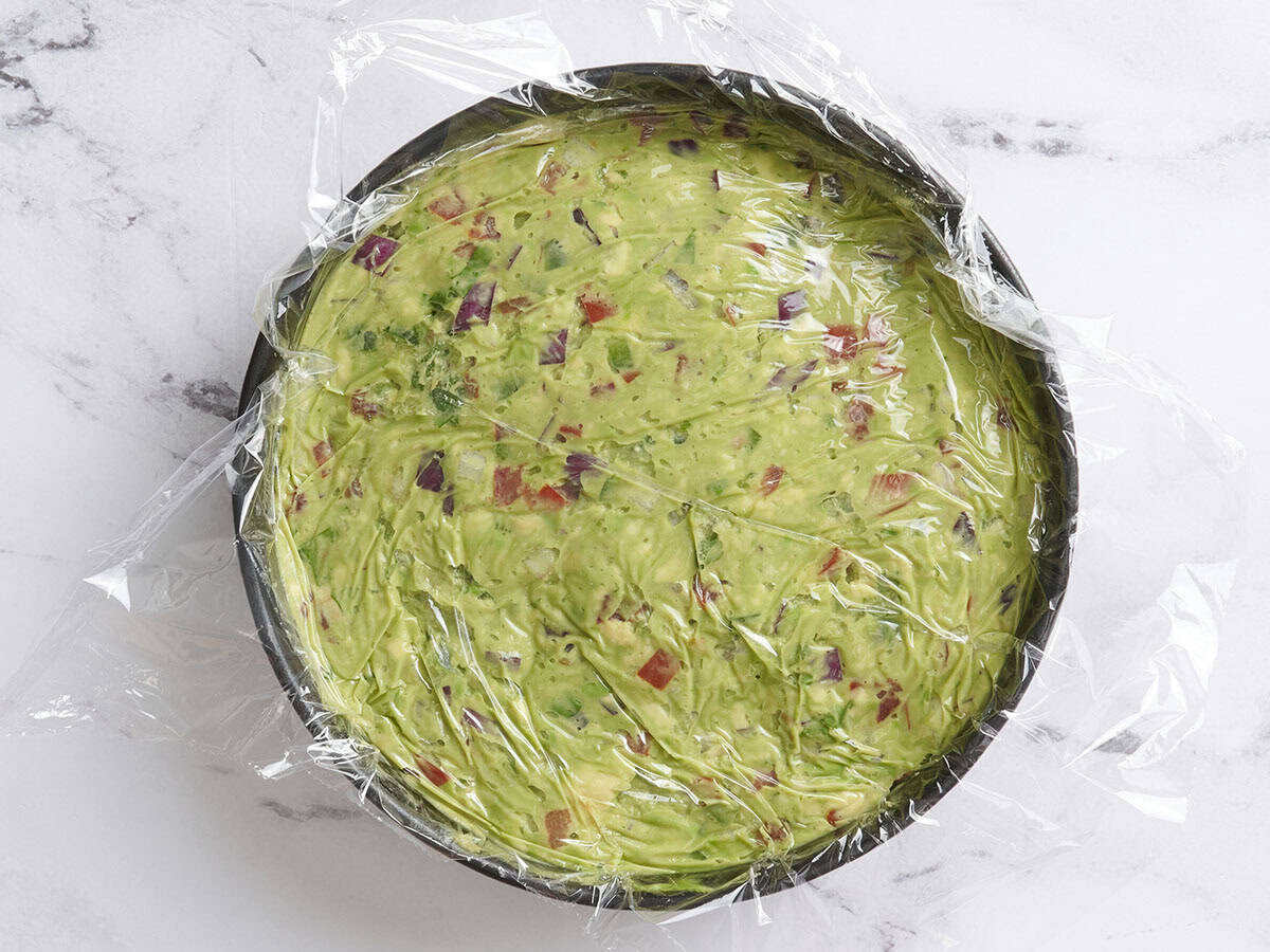 Guacamole in a bowl covered in plastic wrap.