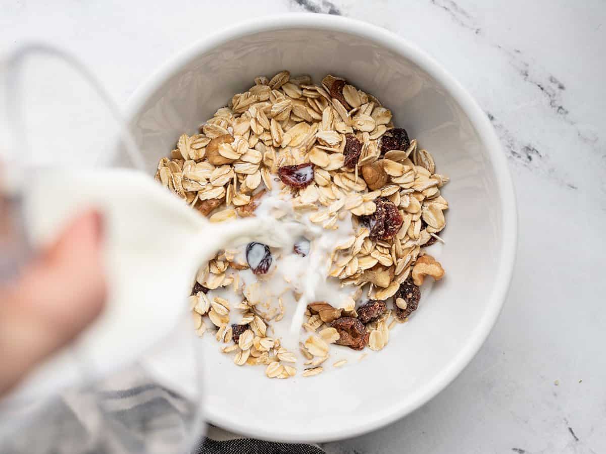 Milk being poured onto a single serving bowl of muesli.