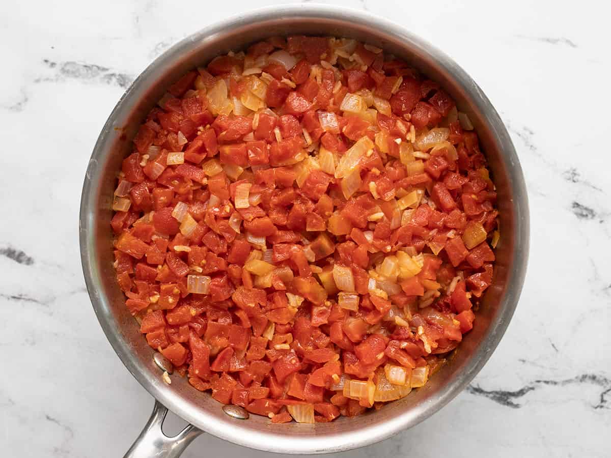 Simmered rice in the pot with tomatoes on top.