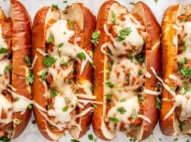 Overhead view of baked meatball subs garnished with parsley.