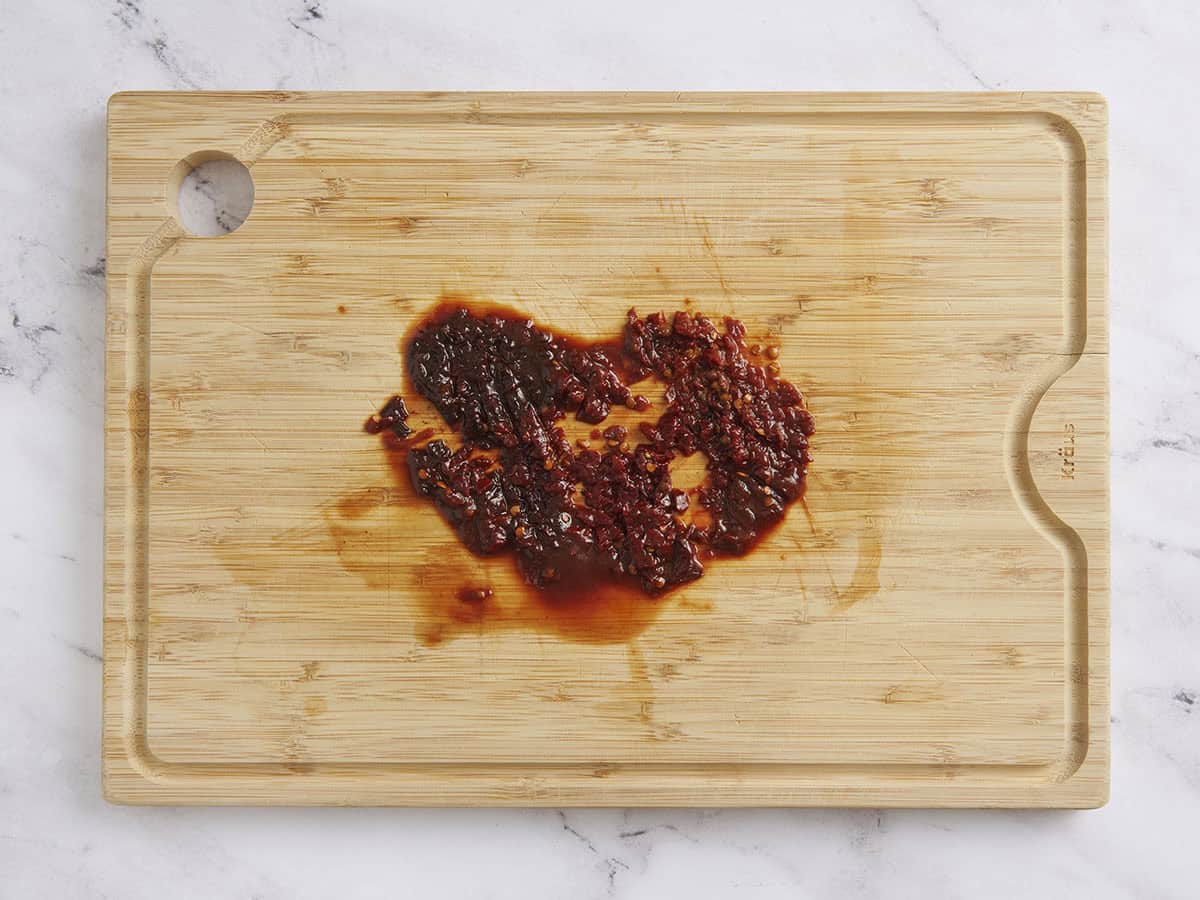 Minced chipotle peppers on a wooden cutting board.