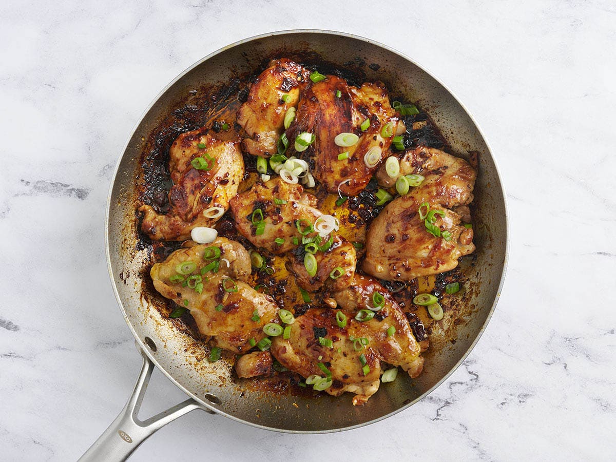 Finished chipotle honey chicken in a skillet topped with green onions.