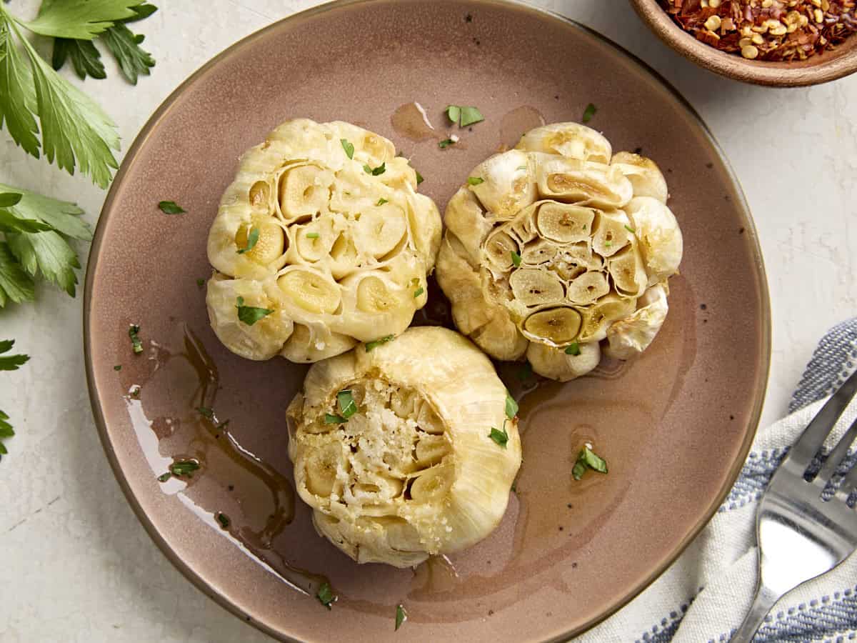 Overhead view of roasted garlic on a plate.