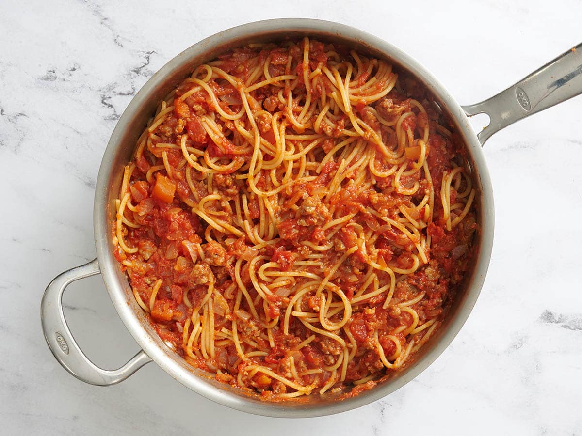 Spaghetti added to the meat sauce for baked spaghetti in a skillet.