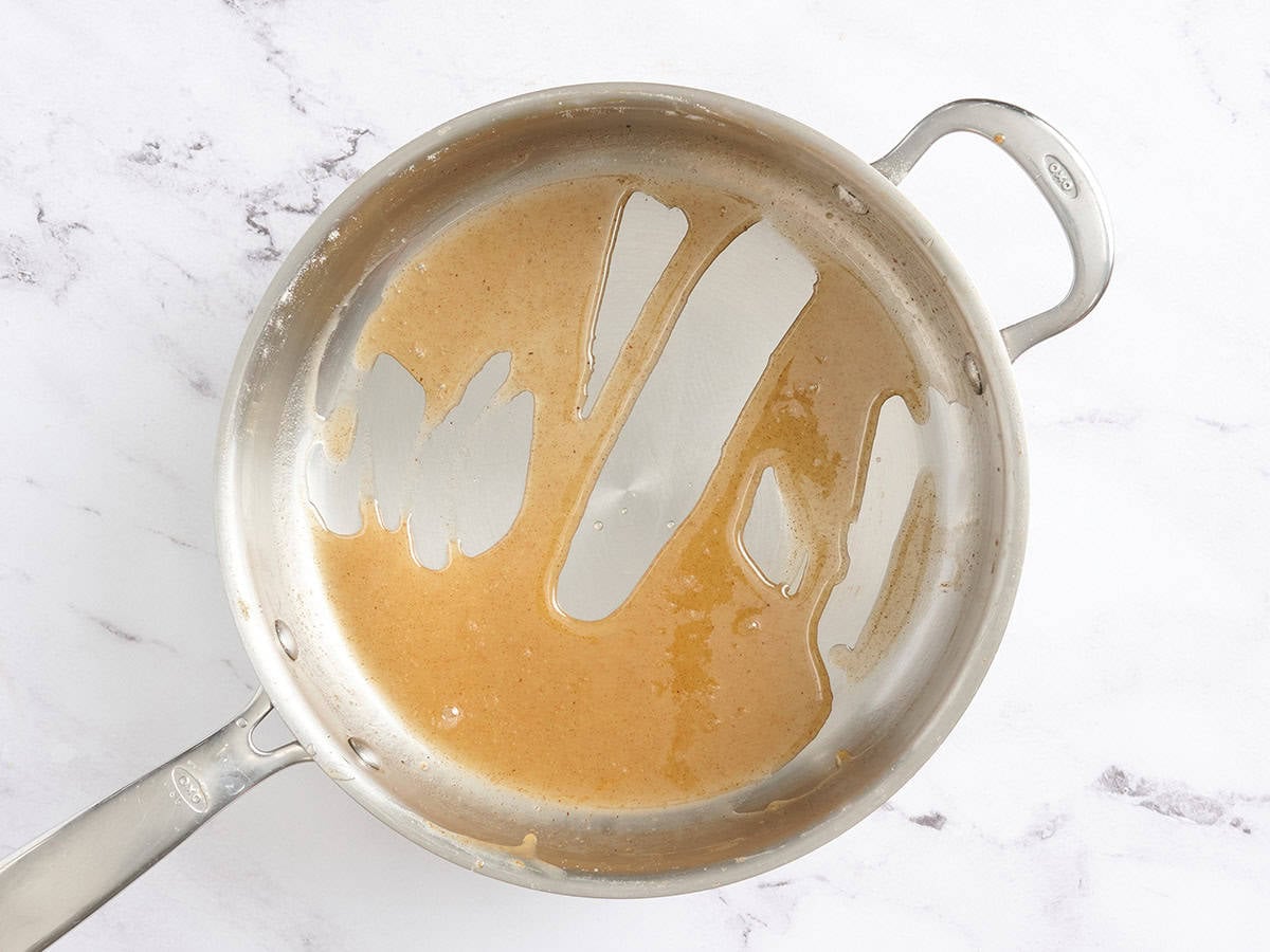 Apple juice in a skillet reduced to make caramel sauce.