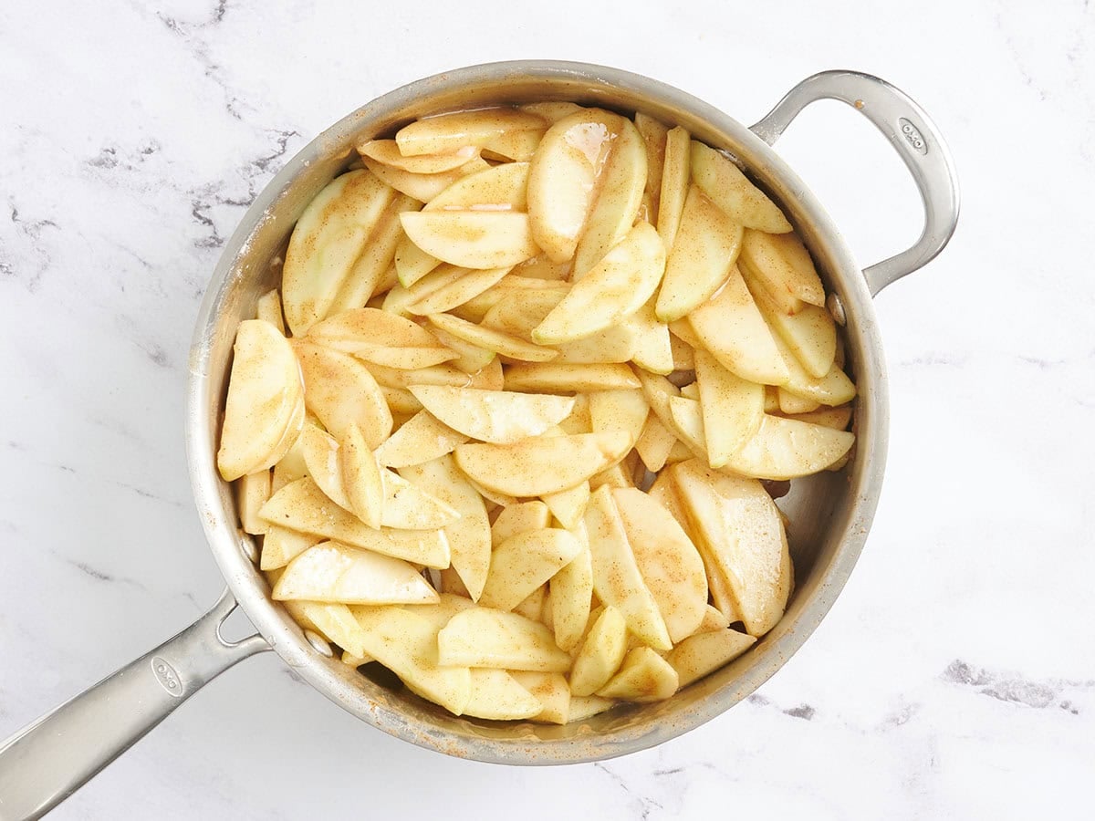 Apple slices cooking down in a skillet.