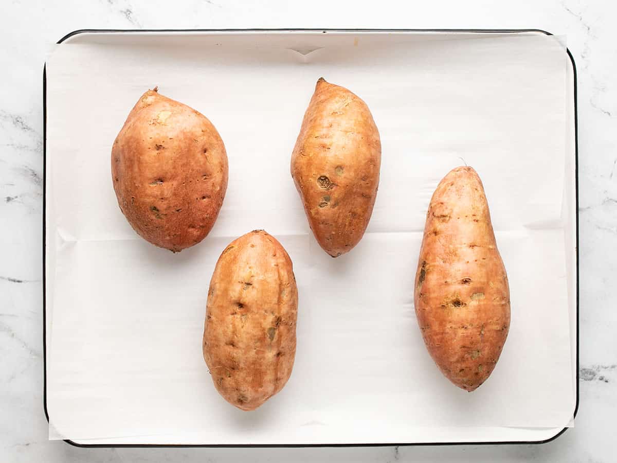 Sweet potatoes on a parchment lined baking sheet.
