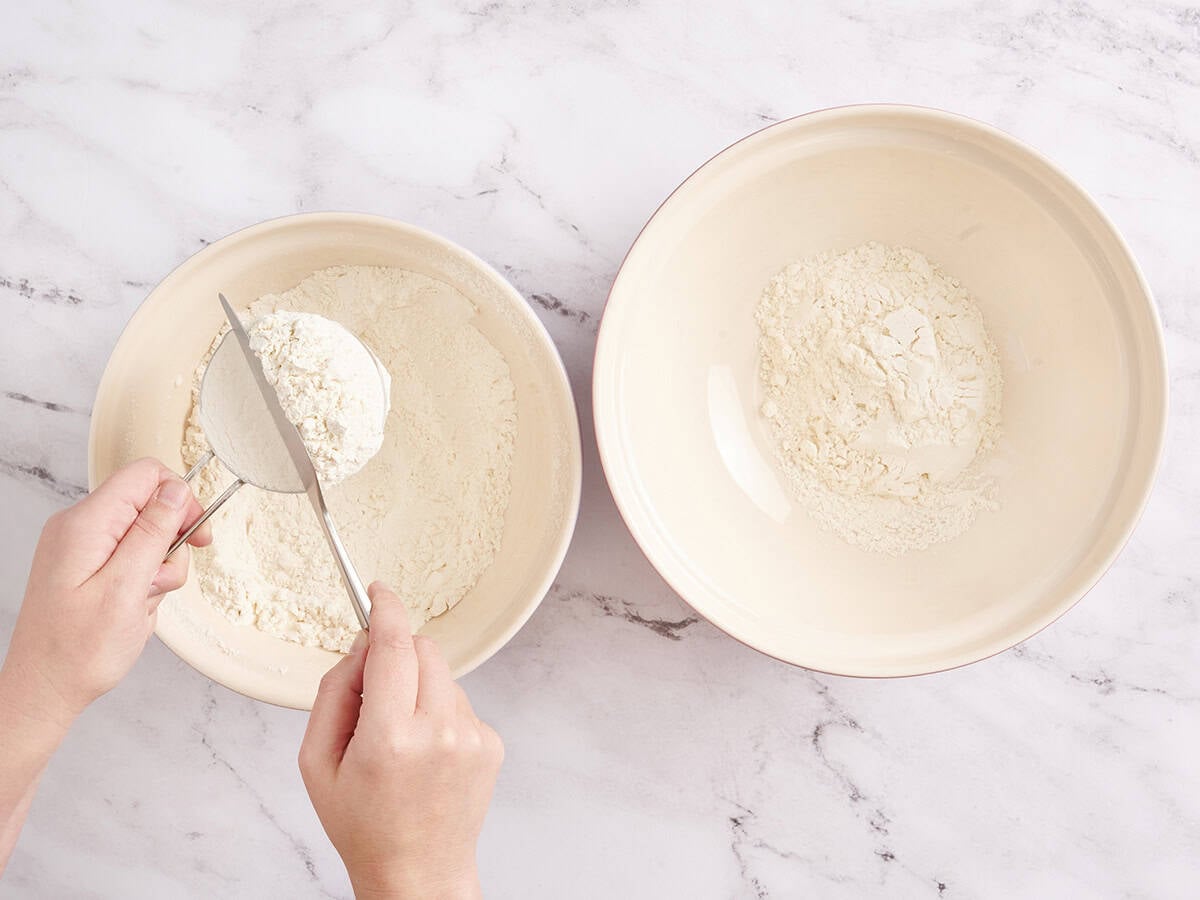 A knife levelling flour in a measuring cup.
