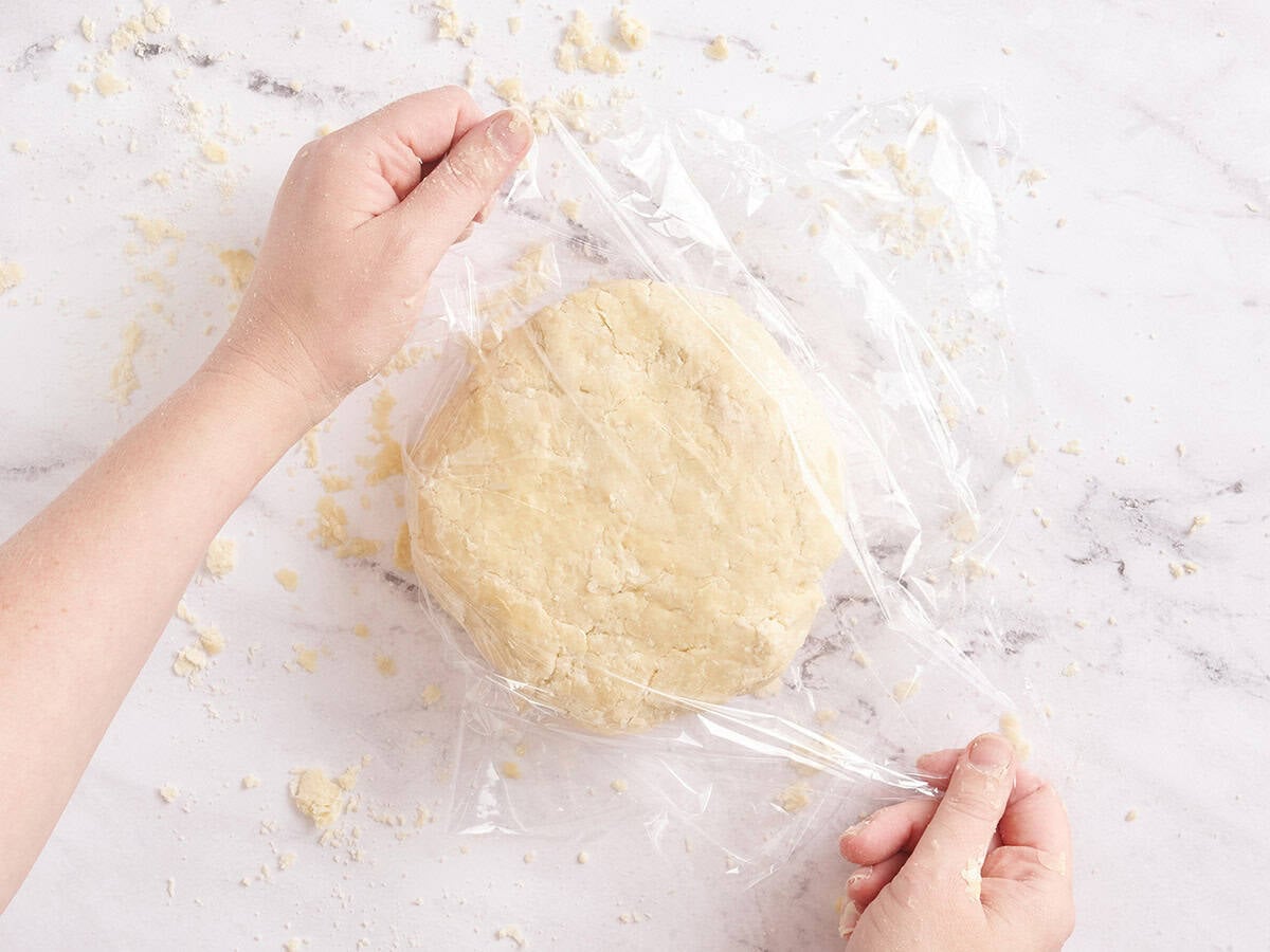 Homemade pie dough covered in plastic wrap.