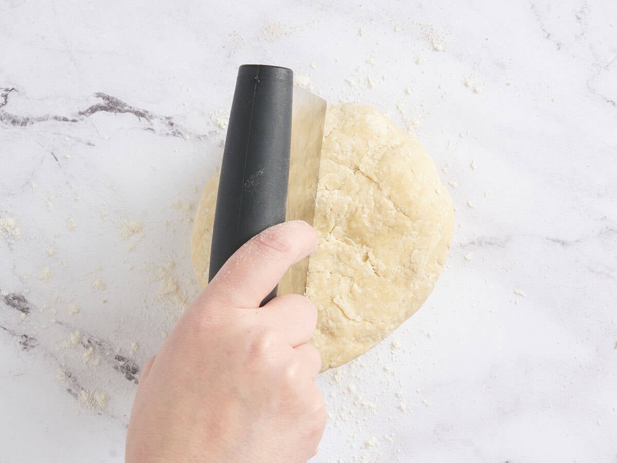 Pie dough being cut into two portions.
