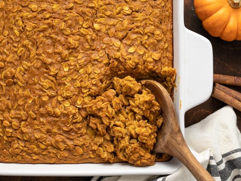 It tastes like dessert, but is healthy enough for breakfast! Baked Pumpkin Pie Oatmeal is a great "fix ahead" breakfast option. Budgetbytes.com close up of pumpkin pie oatmeal being scooped out of the baking dish.