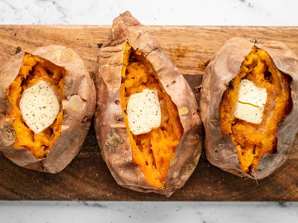 Baked sweet potatoes topped with butter, salt, and pepper.