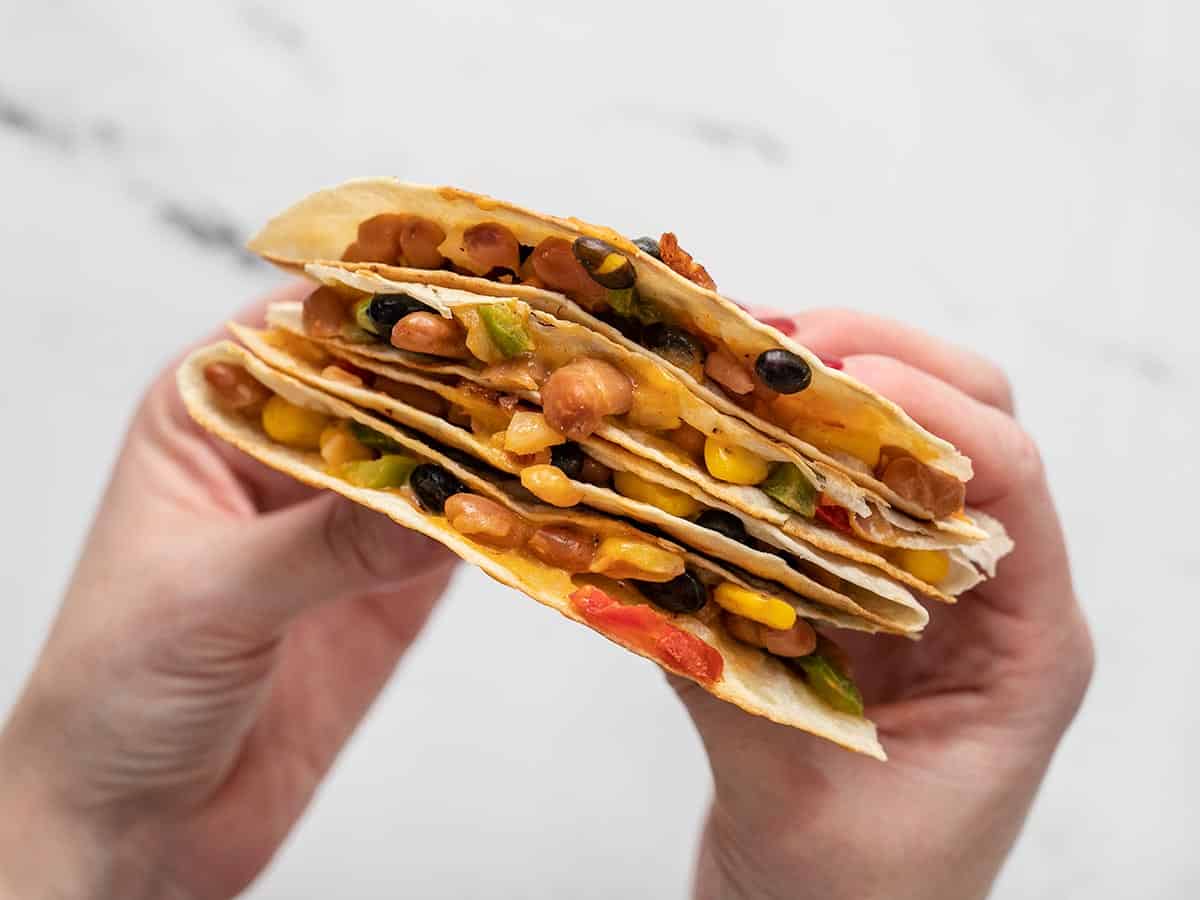 Close up view of stacked quesadillas held in hands..