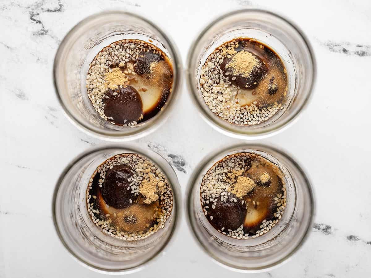 Ingredients for broth in the bottom of four jars.