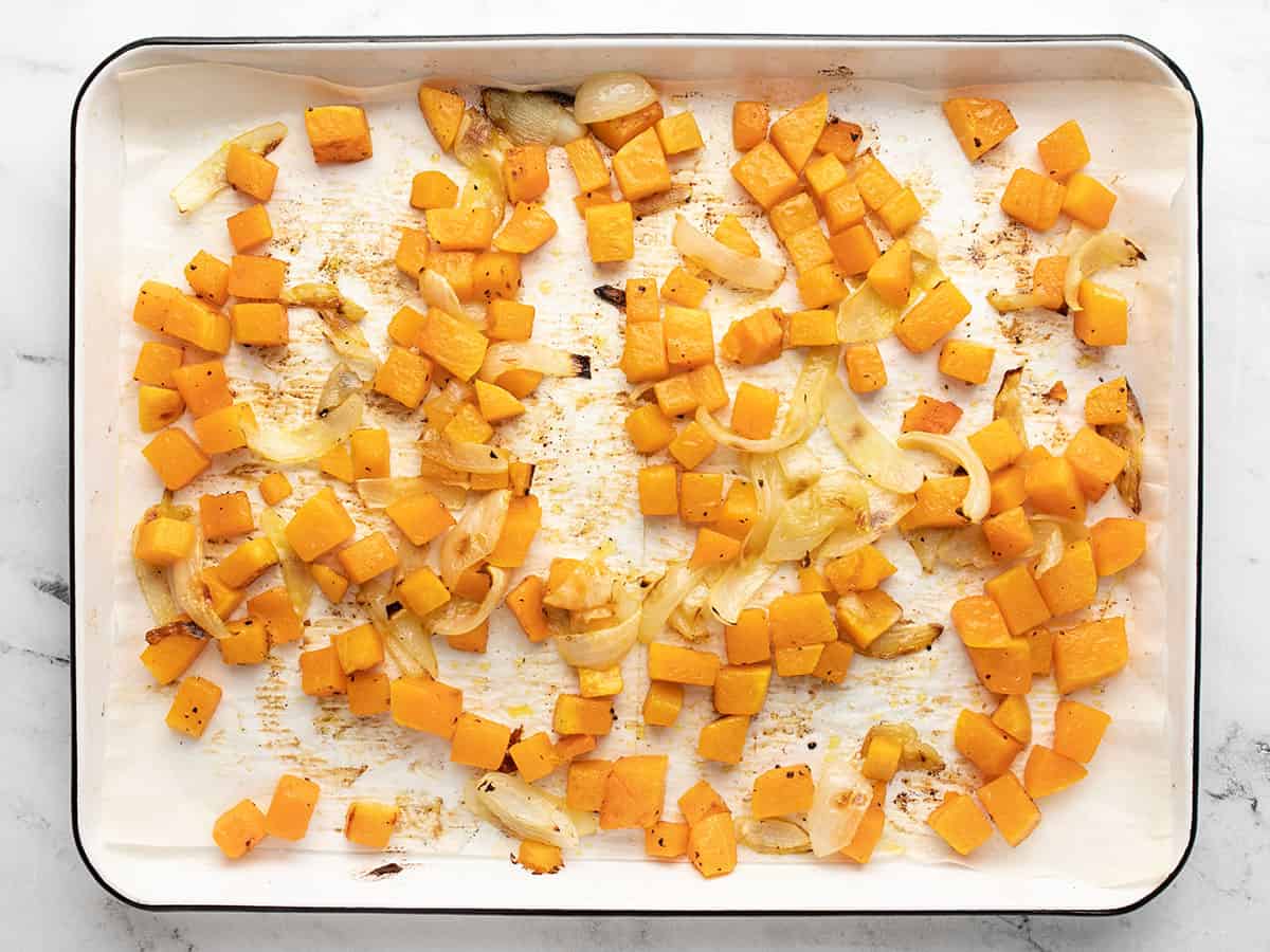 Roasted squash and onions on a baking sheet.
