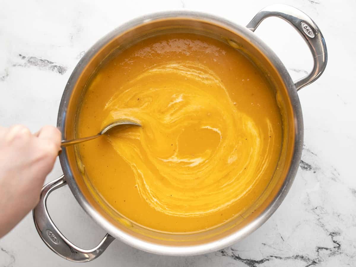 Heavy cream being stirred into the soup.