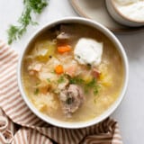 Overhead view of a bowl of kapusniak with sour cream.