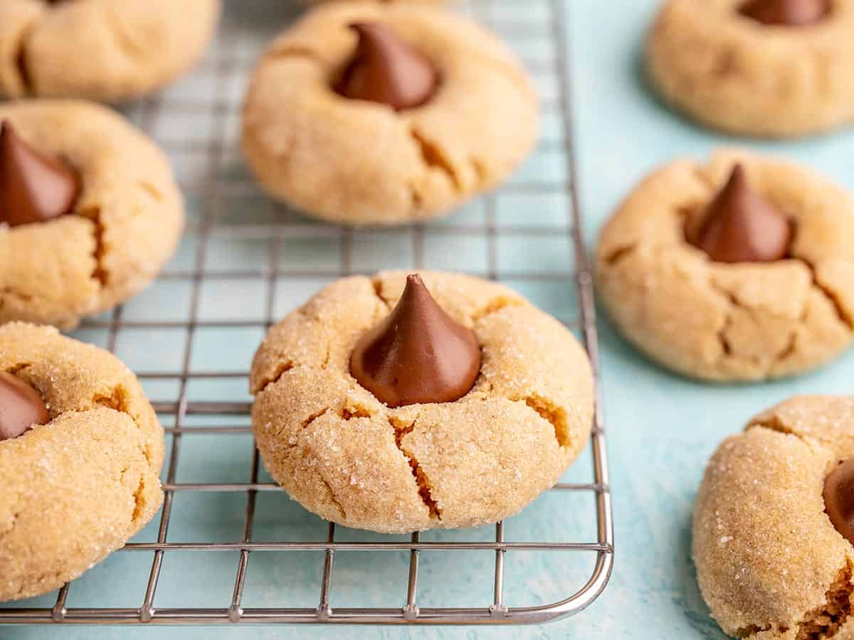 Side view of peanut butter blossoms scattered on the cooling rack.
