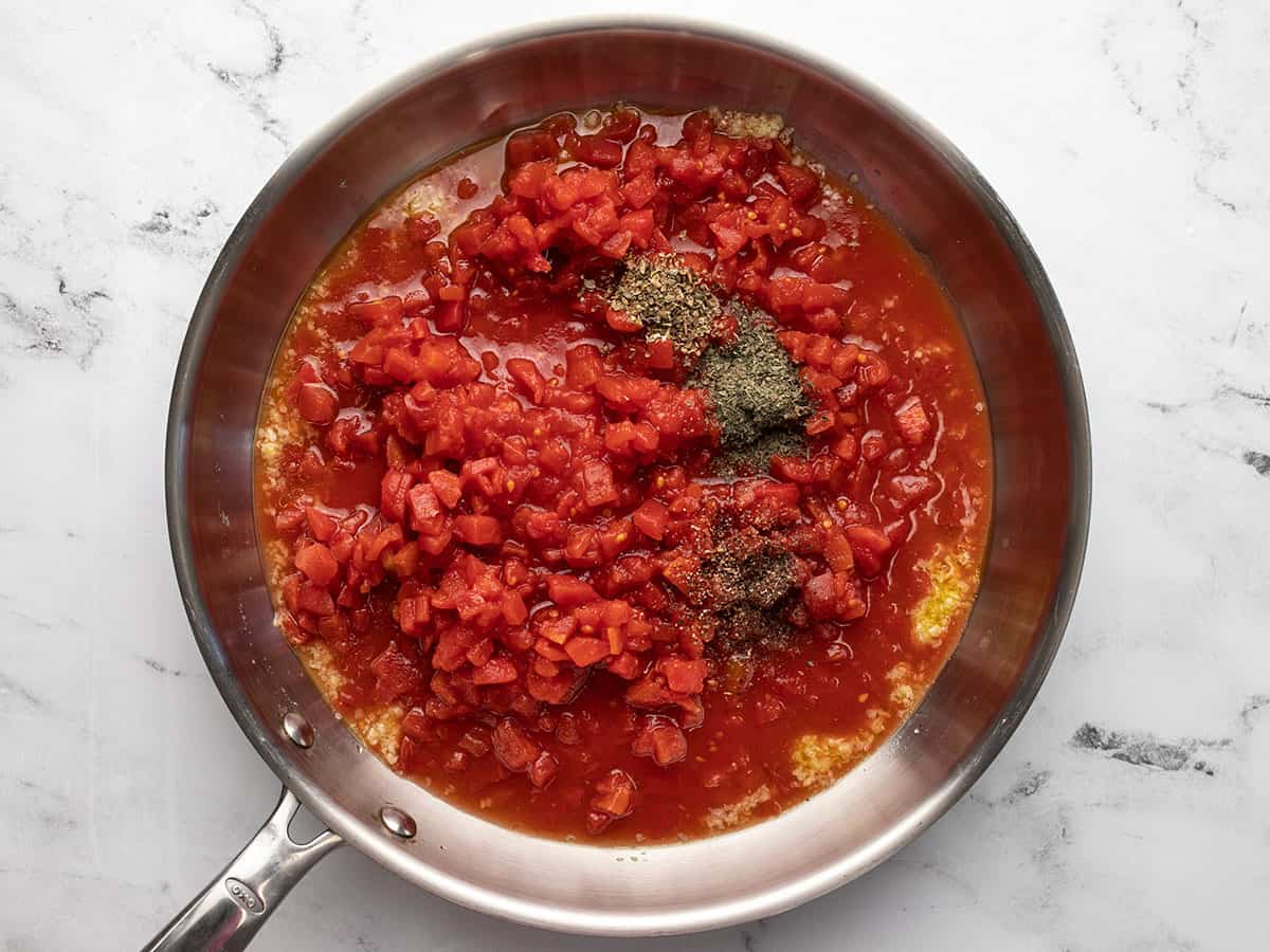 Diced tomatoes and herbs added to the skillet.
