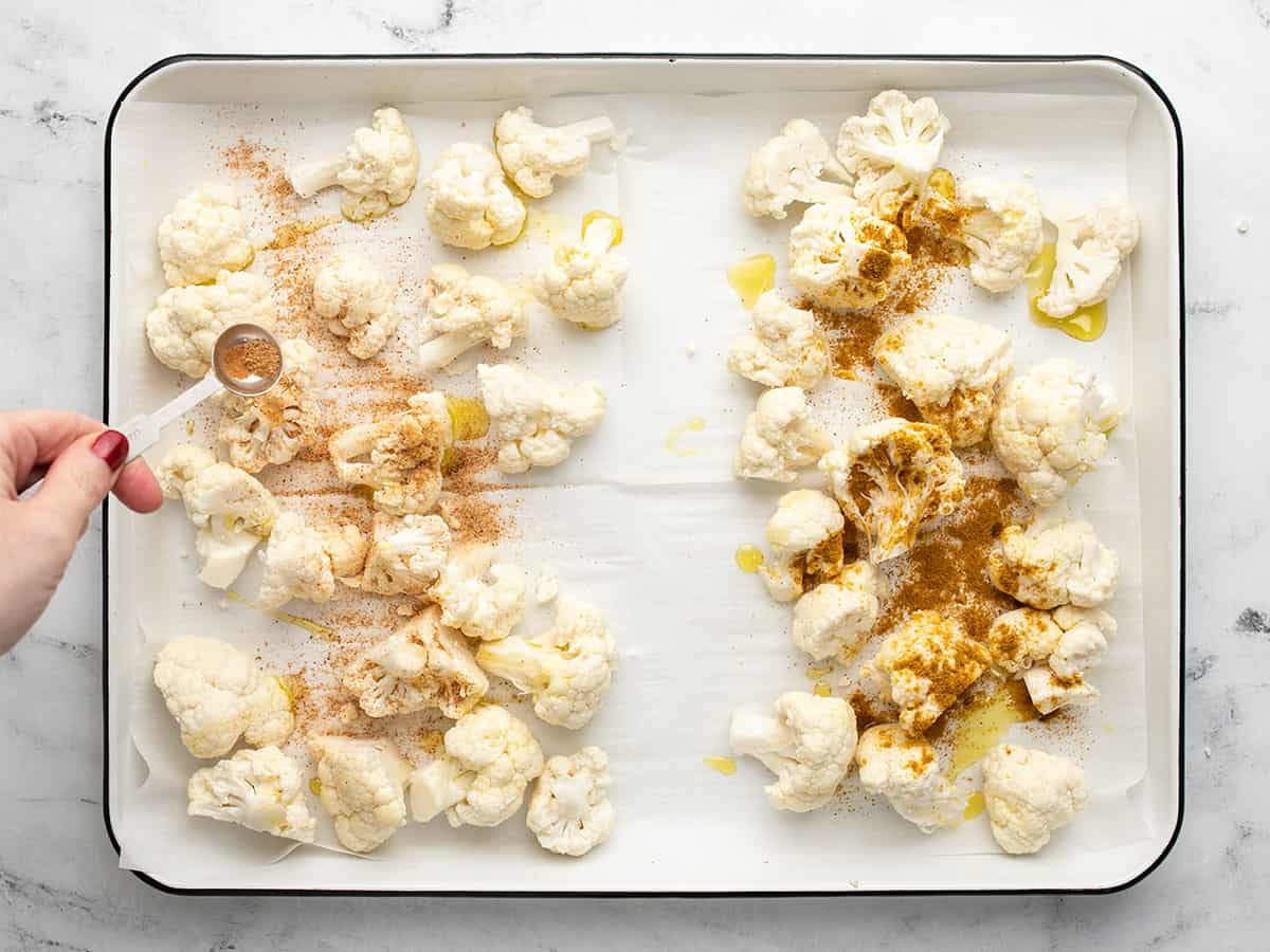 Cauliflower florets on a sheet pan being seasoned.