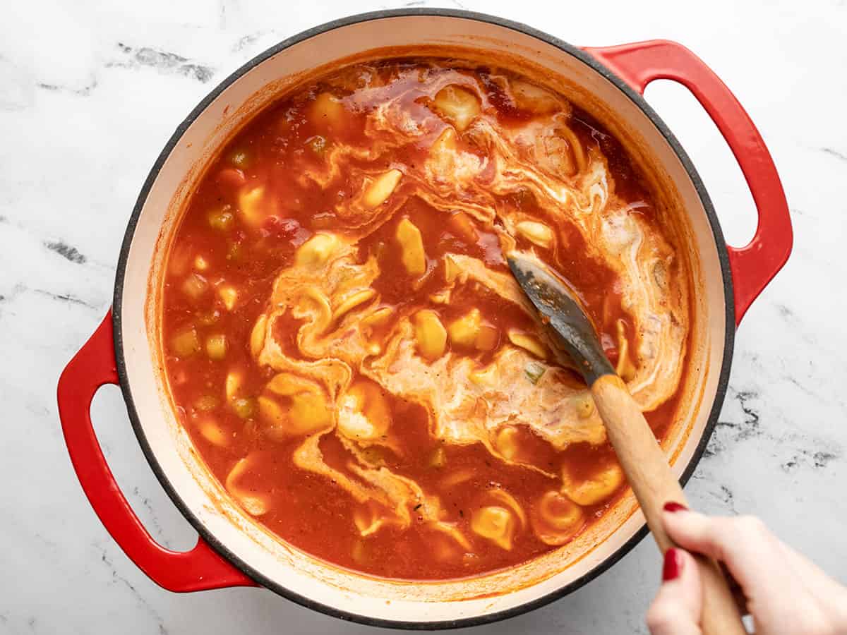 Heavy cream being stirred into the soup.