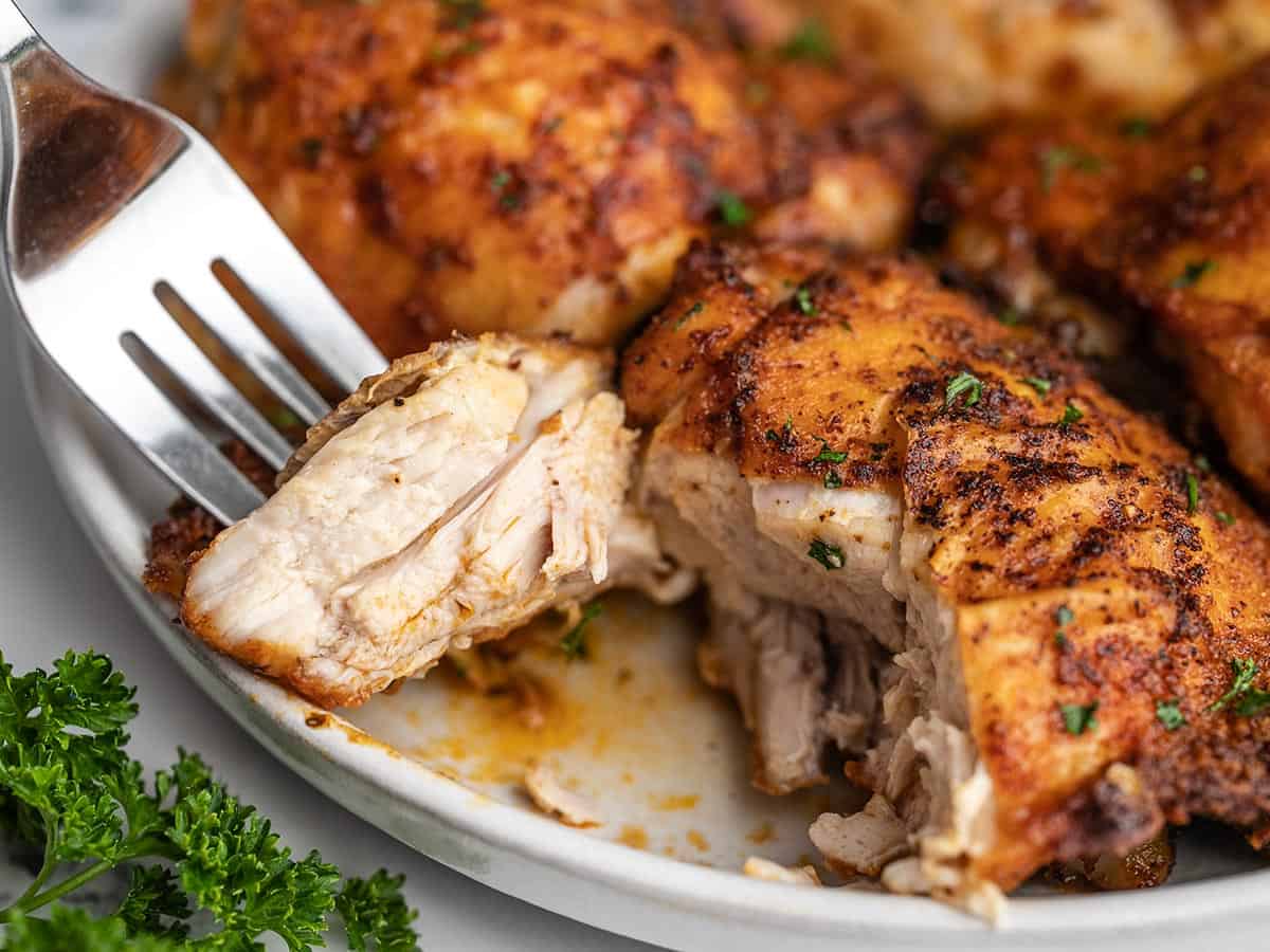 Close up of an air fryer chicken thigh cut open and pierced with a fork.